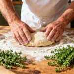 Boulanger européen de 55 ans préparant une pâte à pâtisserie avec des feuilles de thym frais sur un plan de travail en bois